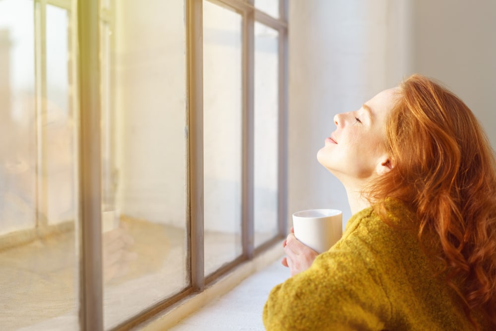 woman looking out a sunny window