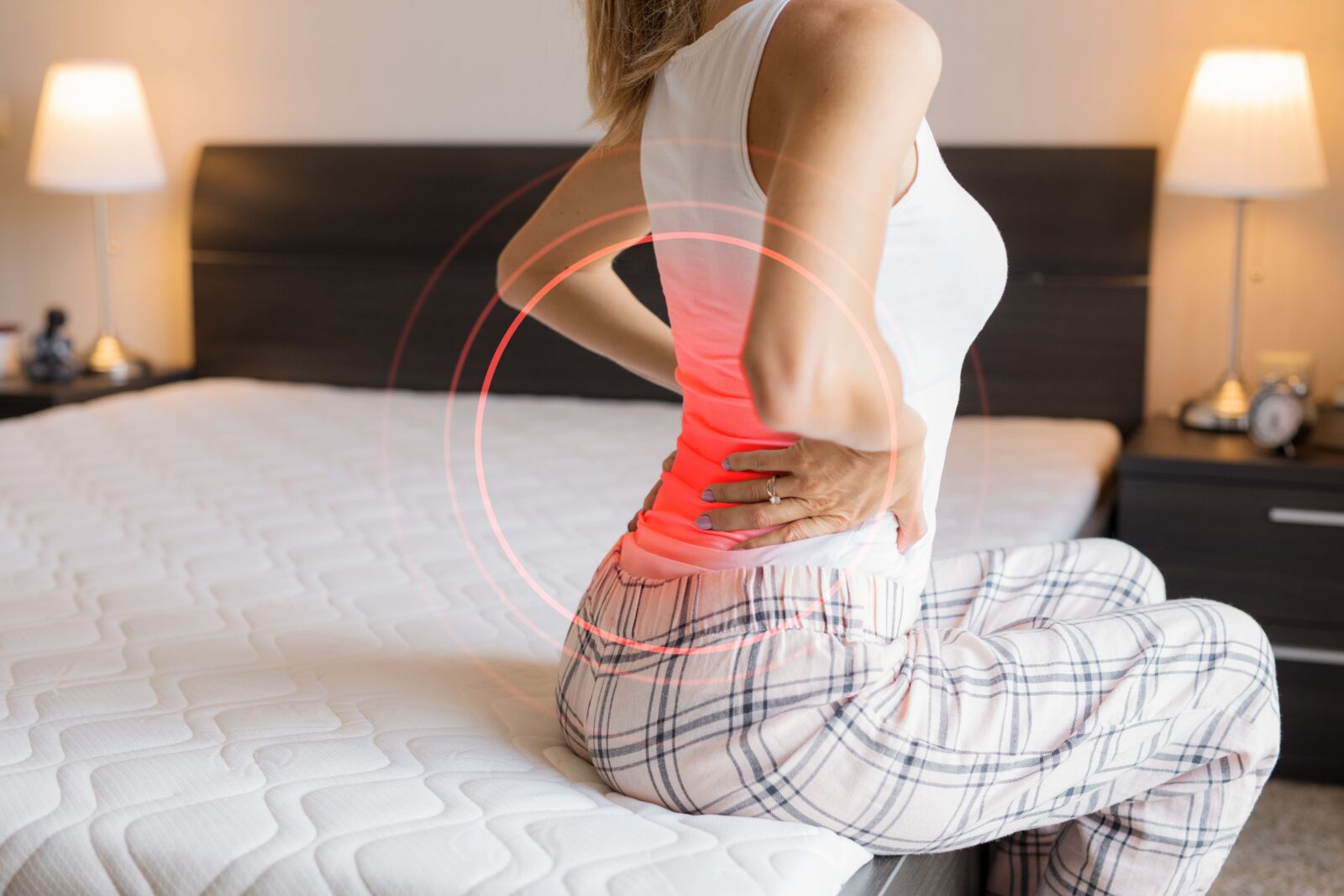 woman sitting on edge of bed in pain