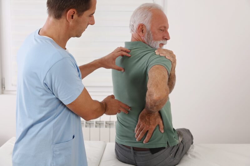 Senior man with back pain. Spine physical therapist and paient. chiropractic pain relief therapy. Age related backache