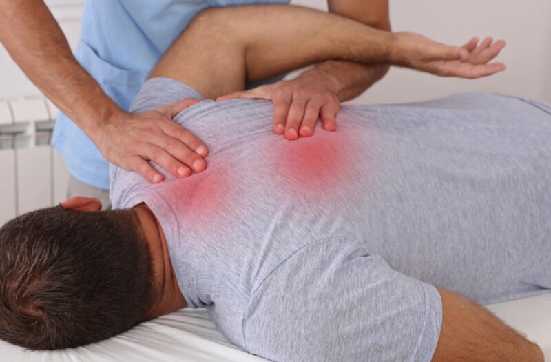 physical therapist massaging man's spine