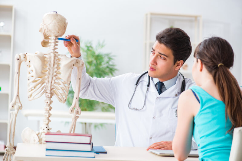 Doctor showing type of injury on skeleton to patient