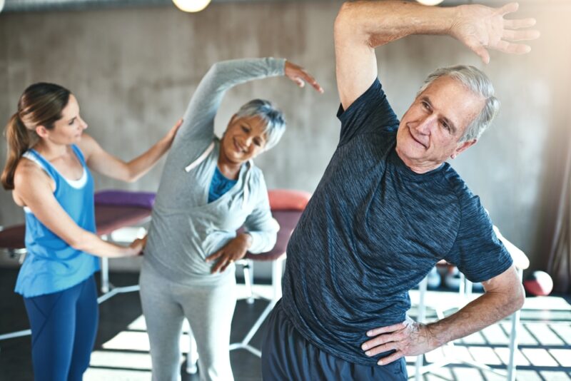 Stretching, support and senior people in physical therapy for help with muscle fitness