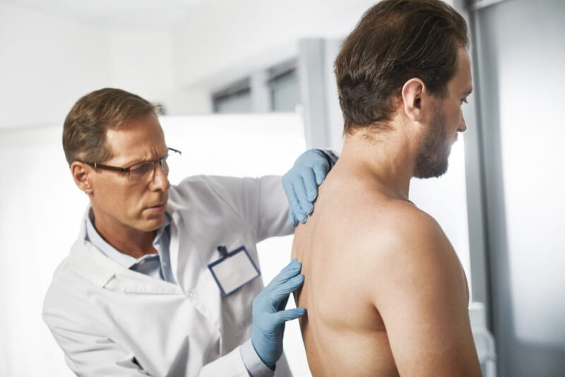 Waist up portrait of male medic exploring thoracic spine to excluding various diseases