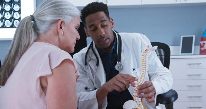 Senior female patient listening to doctor explain reason for her back pain