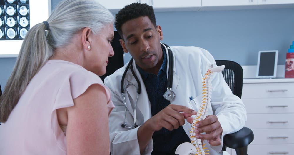 Senior female patient listening to doctor explain reason for her back pain