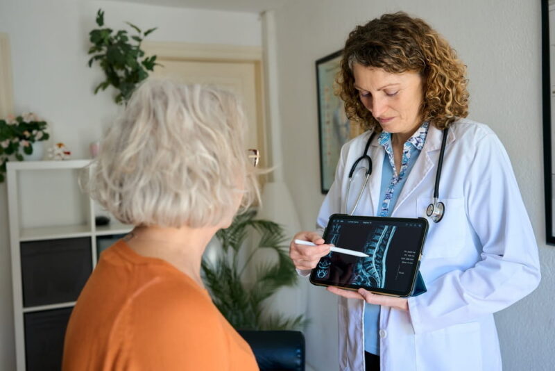 Physiotherapist, man and back pain for consultation, health and wellness for sore muscle or fitness.