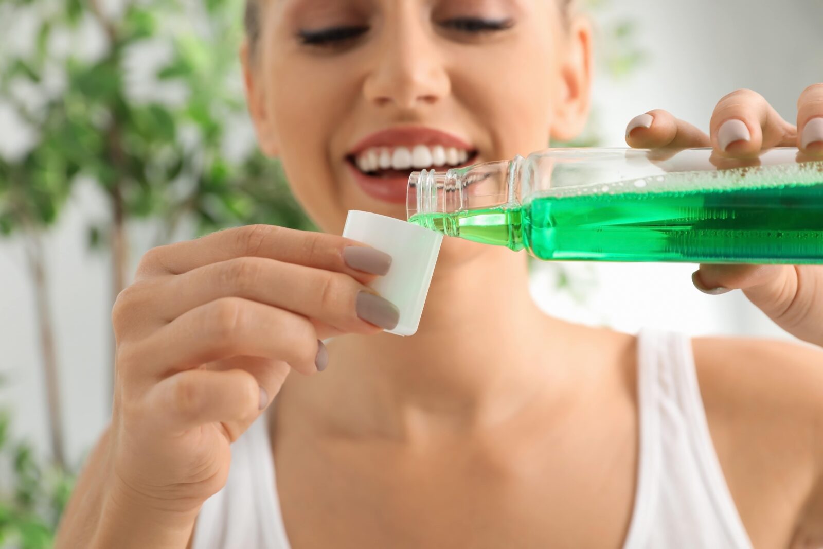 woman smiling and pouring a cup of mouthwash