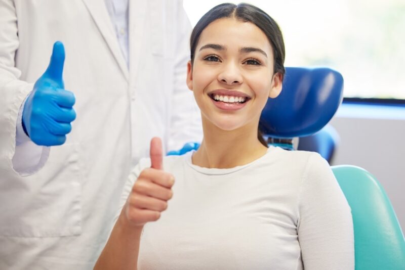 Dentist, client and smile with portrait for thumbs up for success of teeth whitening, oral and dental care