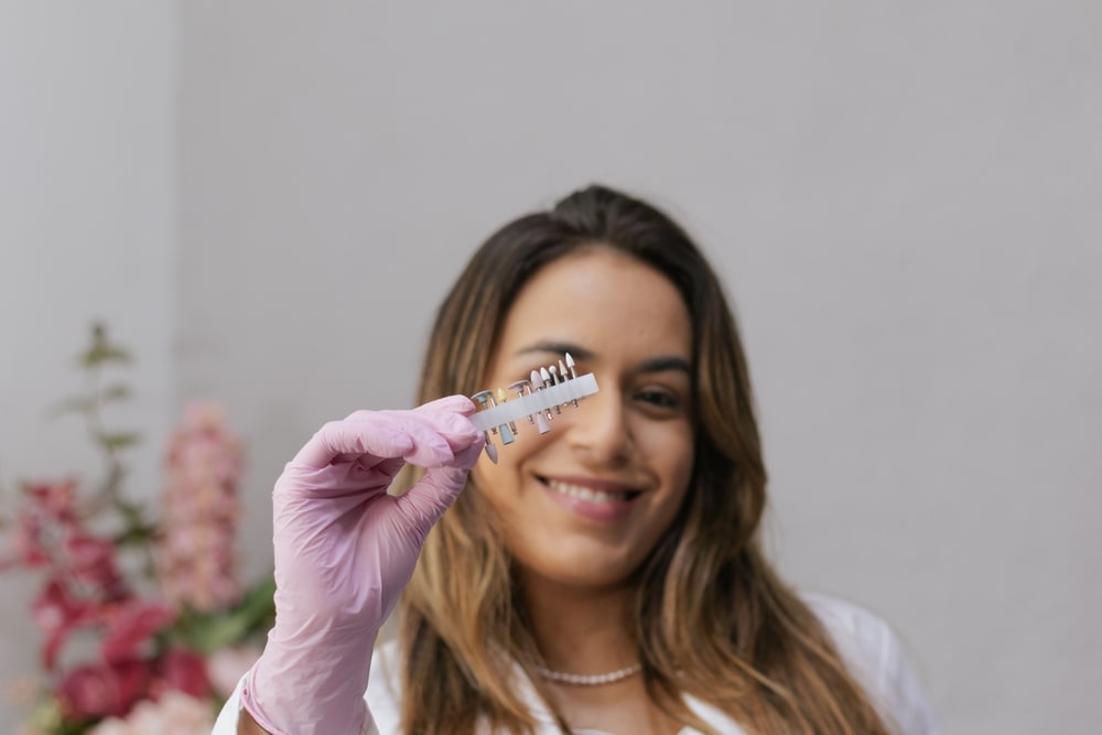 Smiling dentist presenting dental supplies for aesthetic dentistry