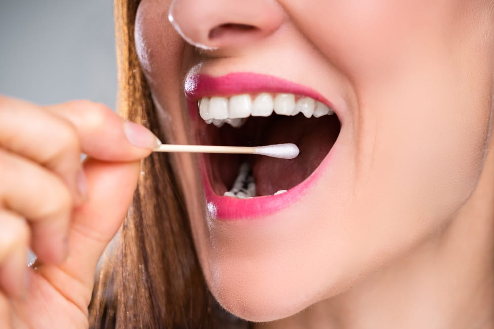 Dentist's Hand Taking Saliva Test From Woman's Mouth With Cotton Swab