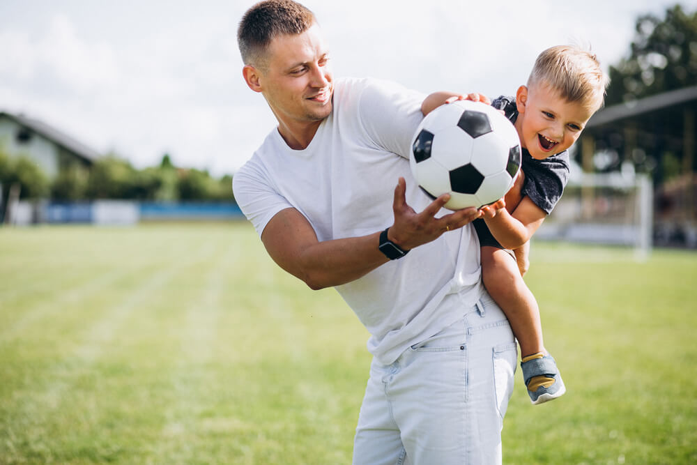 Father playing football with his young son