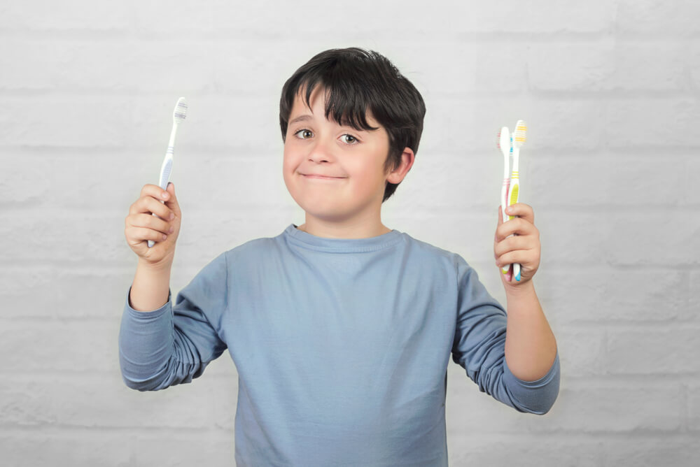 A boy holding multiple tooth brushing in his both hand