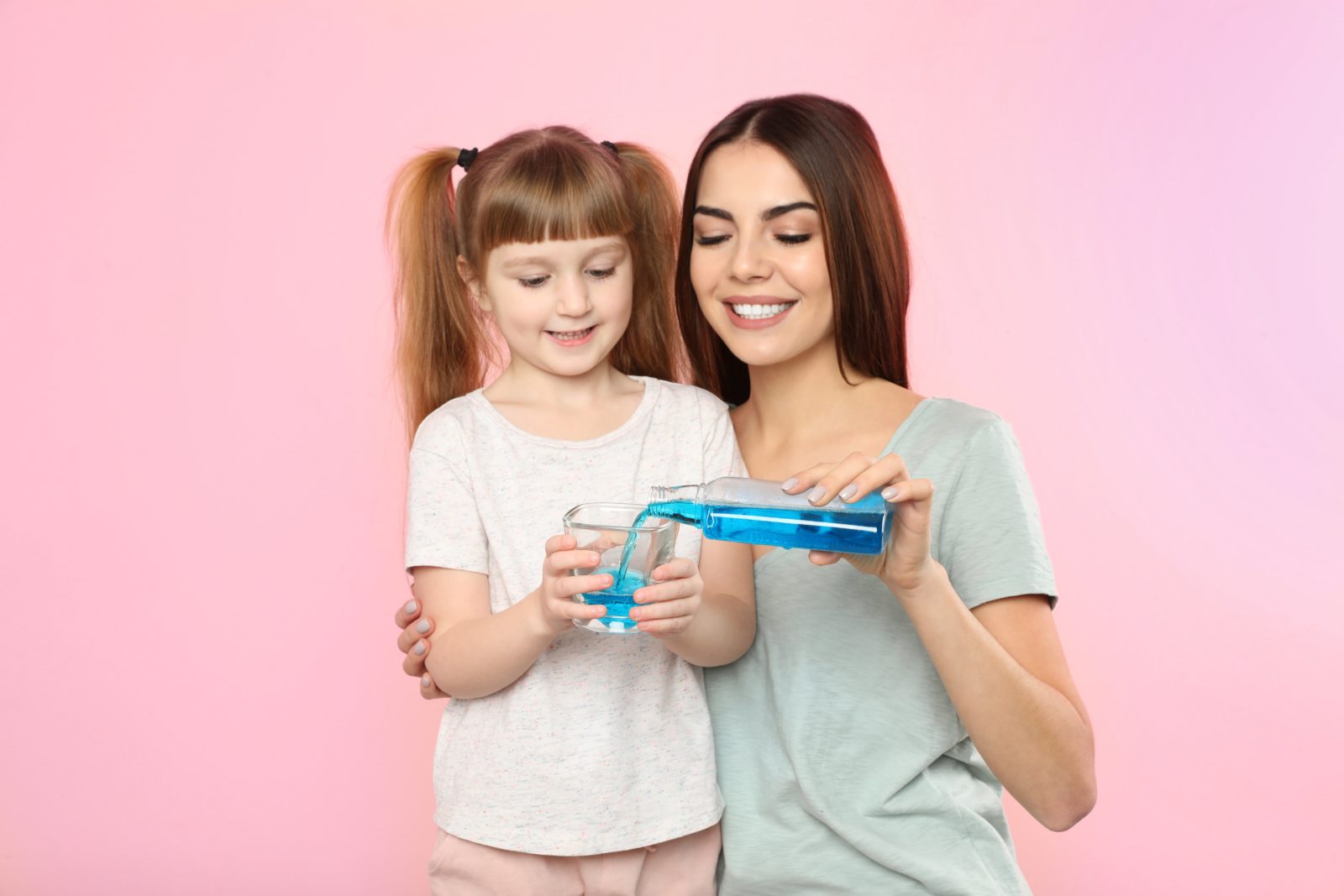 mother helping her daughter with mouthwash