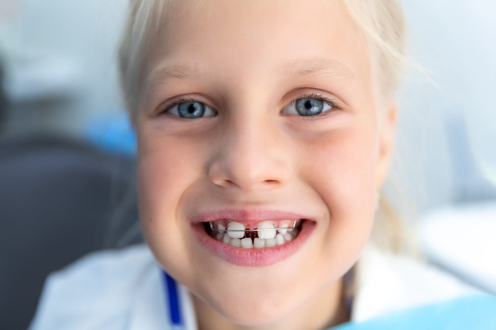 young girl with large gap between her teeth wearing an orthodontic appliance