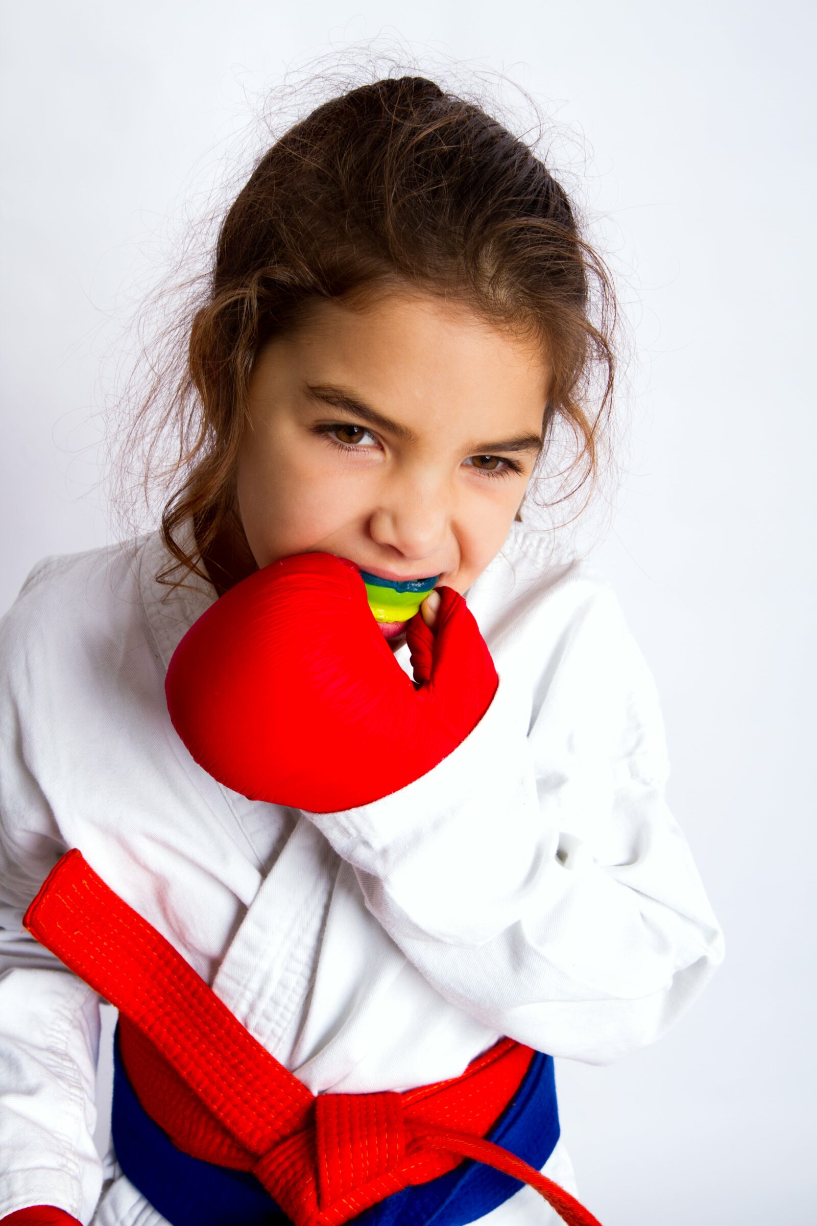 young girl in karate outfit putting in a mouthguard