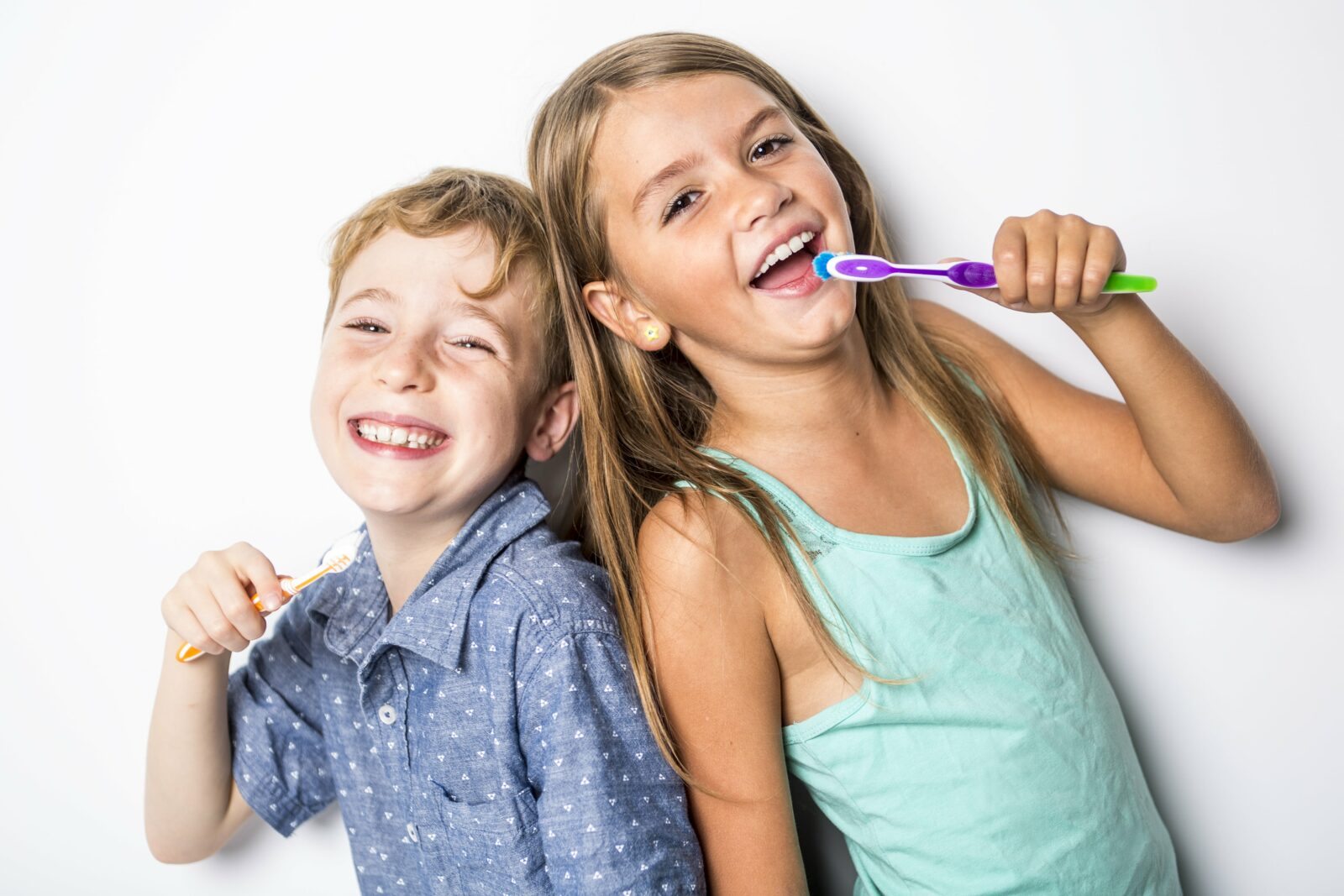 brother and sister brushing their teeth back to back