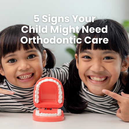 two young girls smile while pointing at teeth model