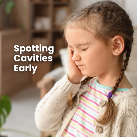 A young girl clutches the side of her cheek, eyes closed, at home.