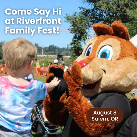 A mascot character resembling a squirrel gives a high-five to a child wearing a tie-dye shirt outdoors.