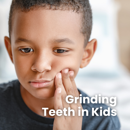 A child rests their hand against their cheek as if their mouth is in pain