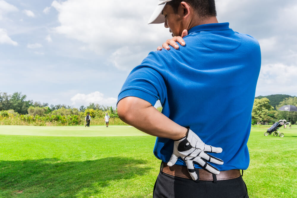 adult male stretching after sports injury while playing golf