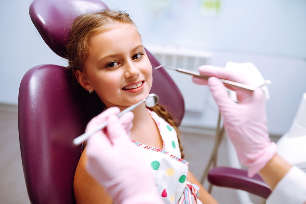 Lovely little girl smiling while talking with the pediatric dentist after