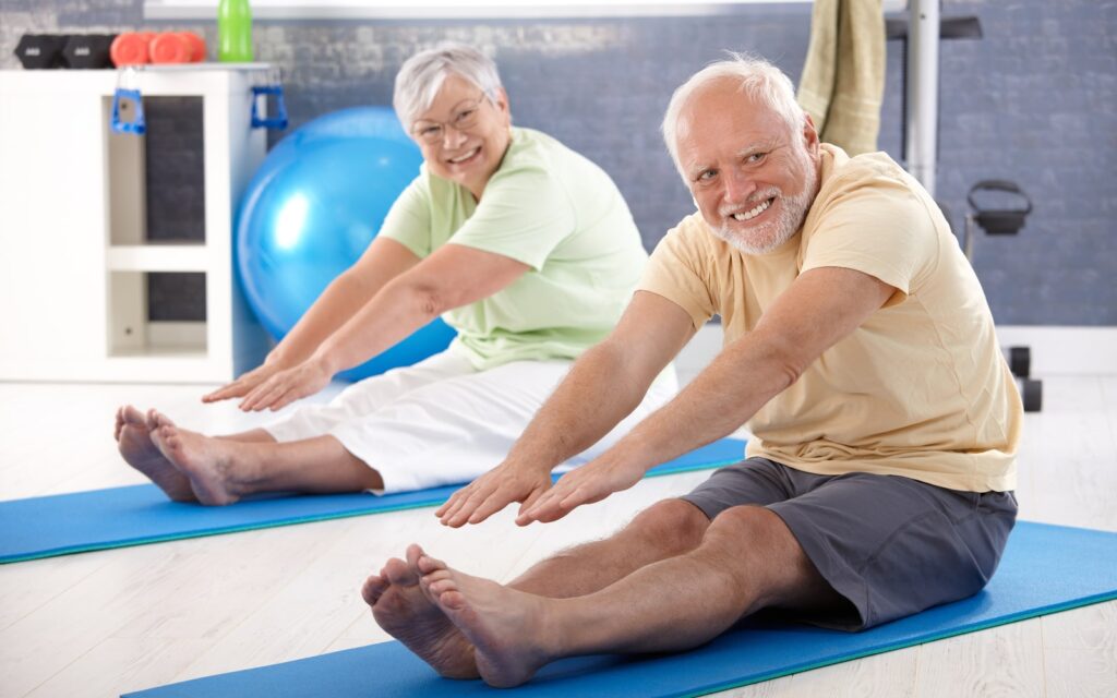 Elderly couple stretching in the gym.