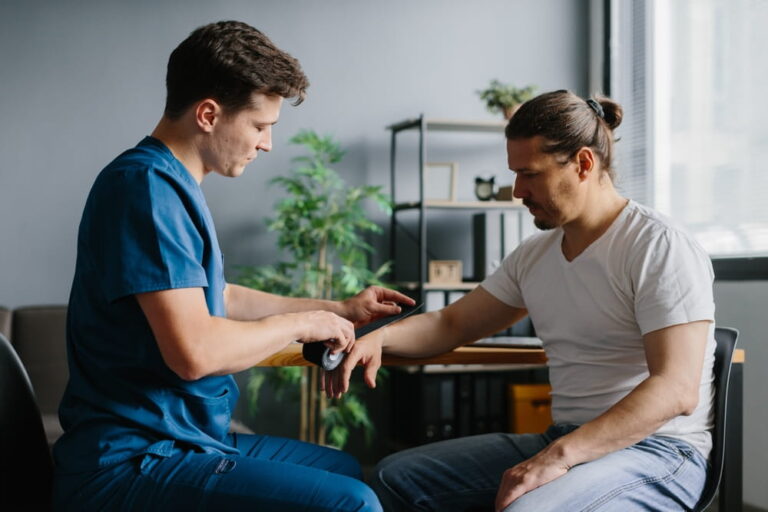 Physician preparing kinesiology tape for arm treatment on a patient.