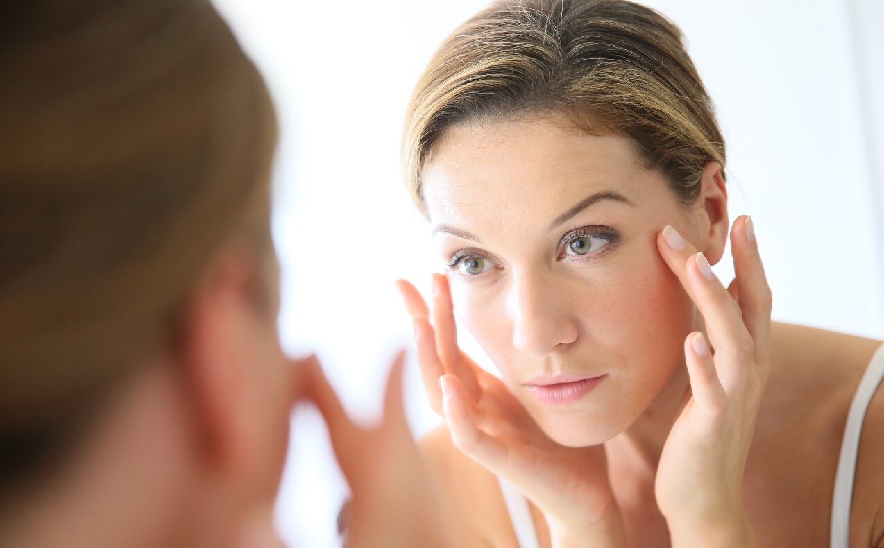 shutterstock_239297989 (1) Aging woman looking in mirror at wrinkles