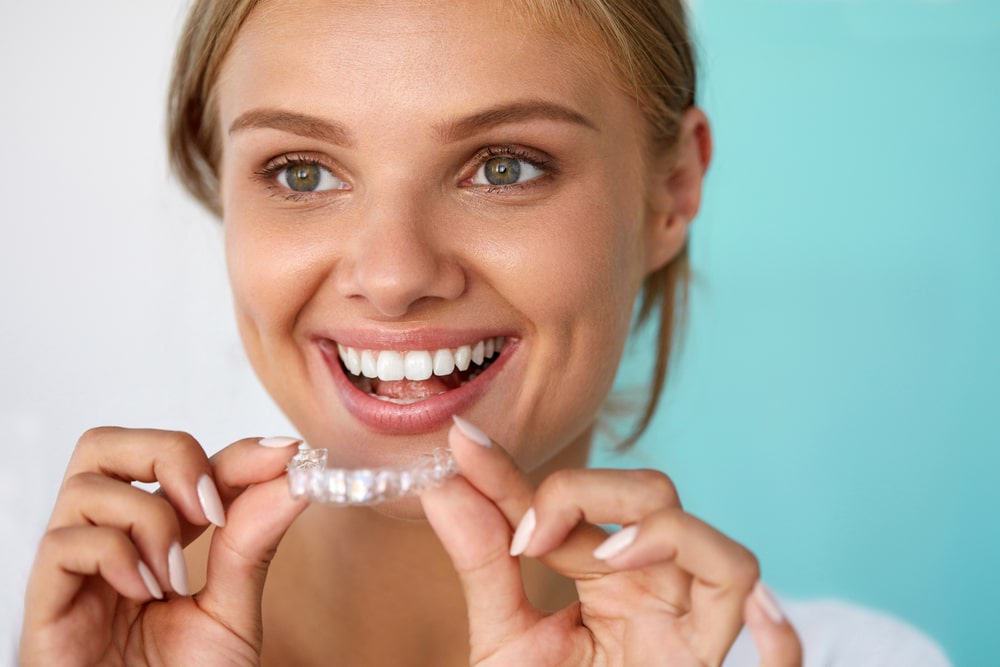 woman holding clear correct aligner