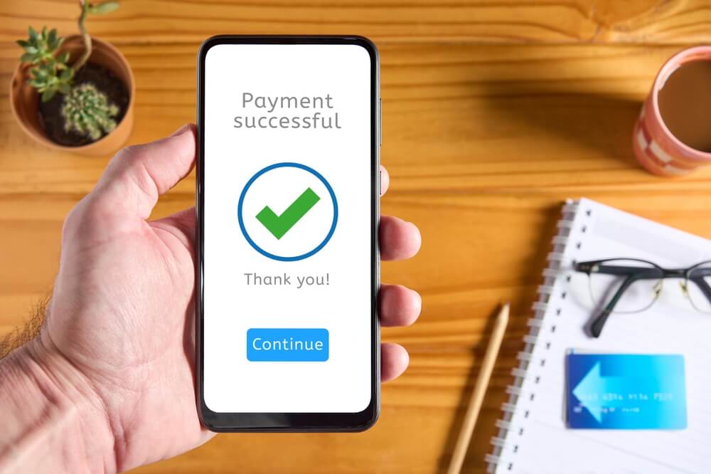 man is holding his phone showing that his payment was successful
