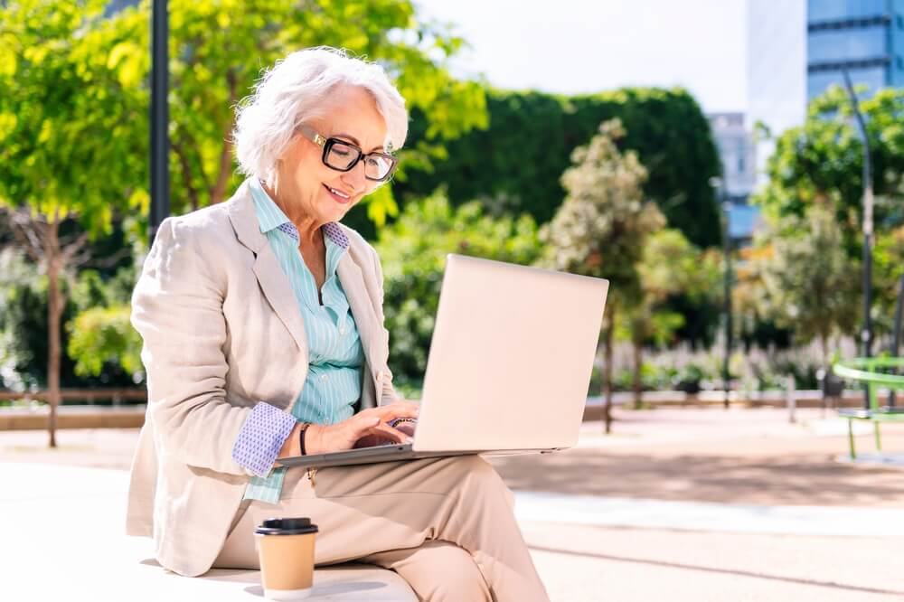 woman is filling out a survey on her laptop while sitting outside