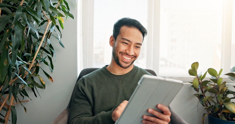 man is smiling at his tablet as he makes an appointment