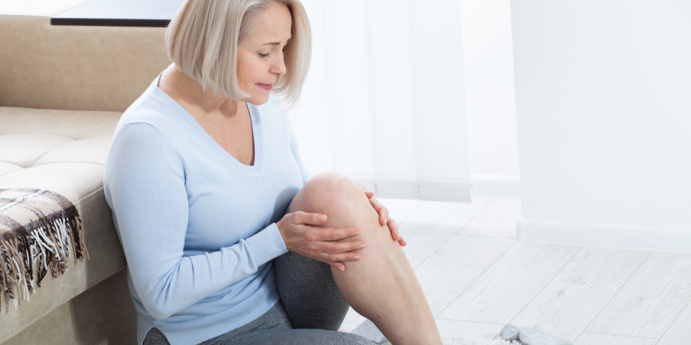 Middle-aged woman suffering from pain in leg at home, closeup.