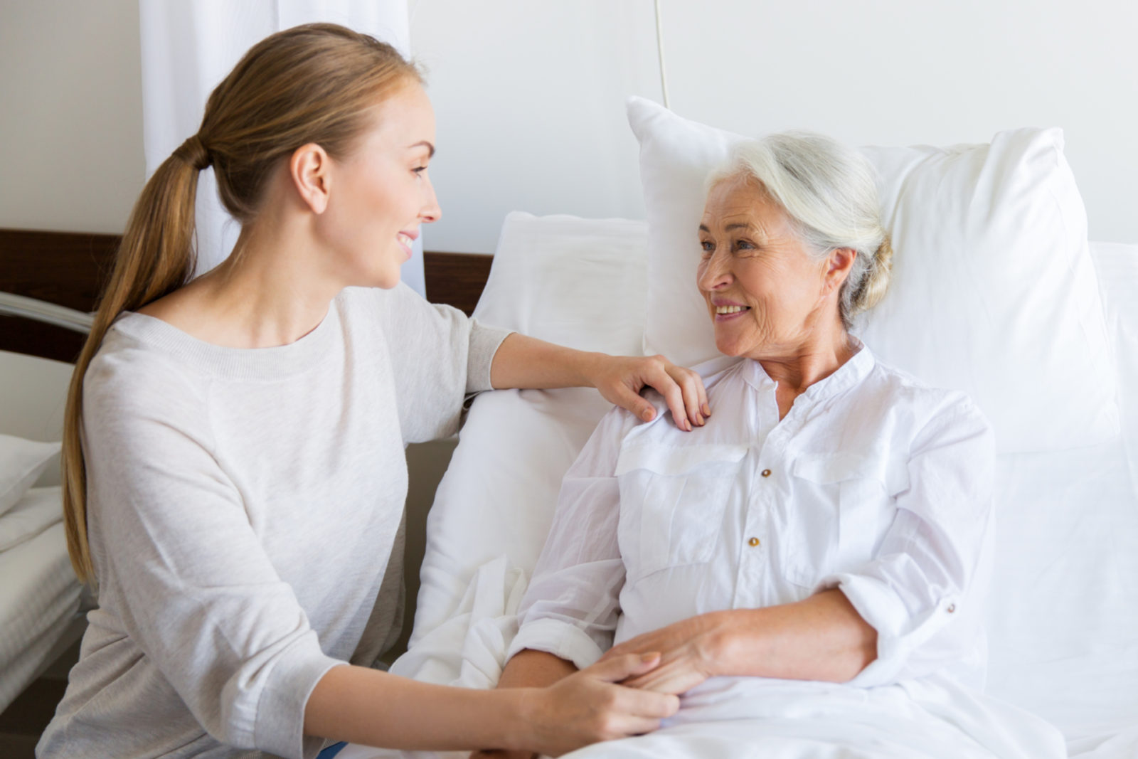 daughter visiting and cheering her mother lying in bed