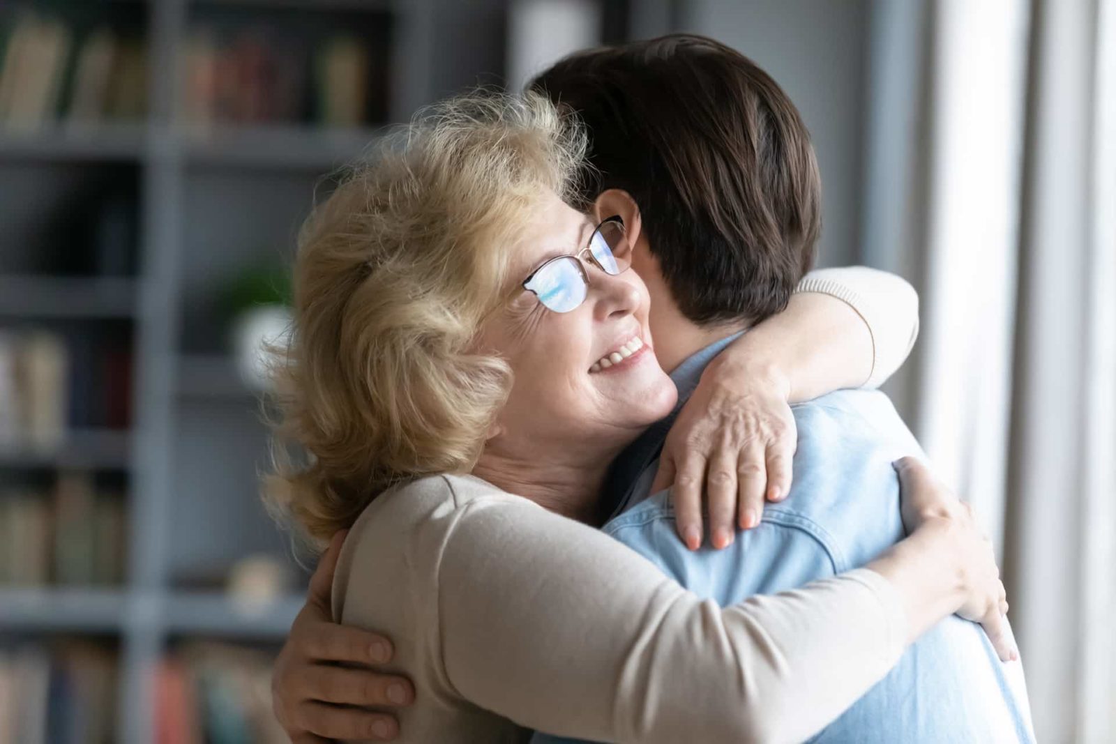 elderly mother in glasses closed eyes enjoy moment strong cuddles adult son