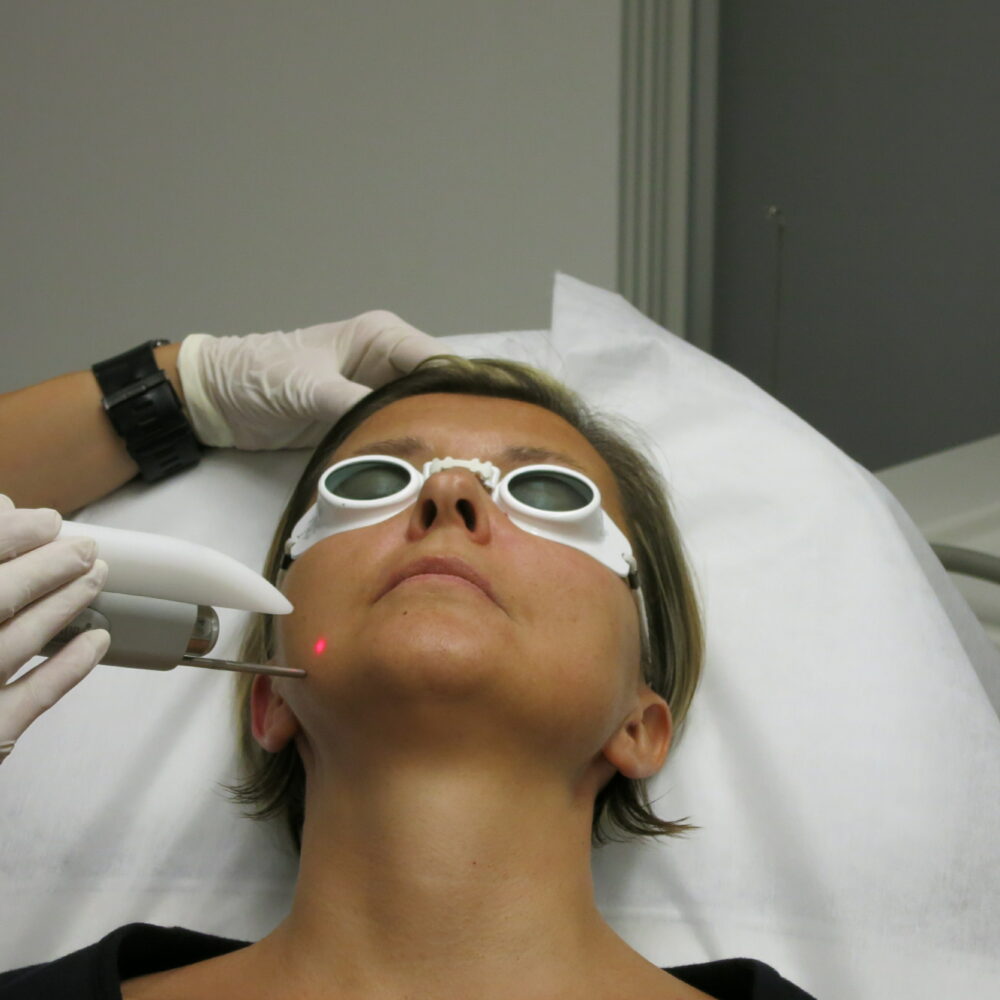 A cosmetic procedure with microcurrent injections in a beauty salon is performed for an aged woman