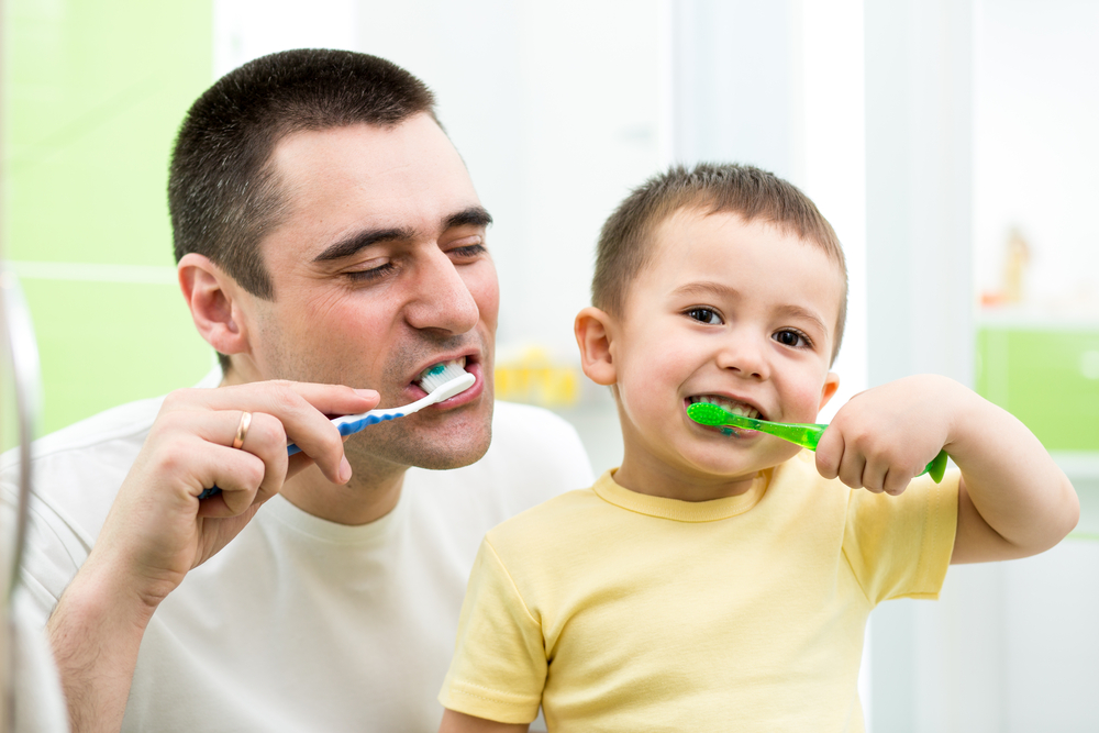 father and kid son brushing teeth in bathroom