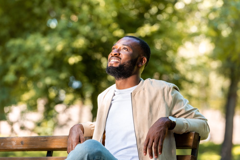 smiling man sitting on wooden bench and looking up
