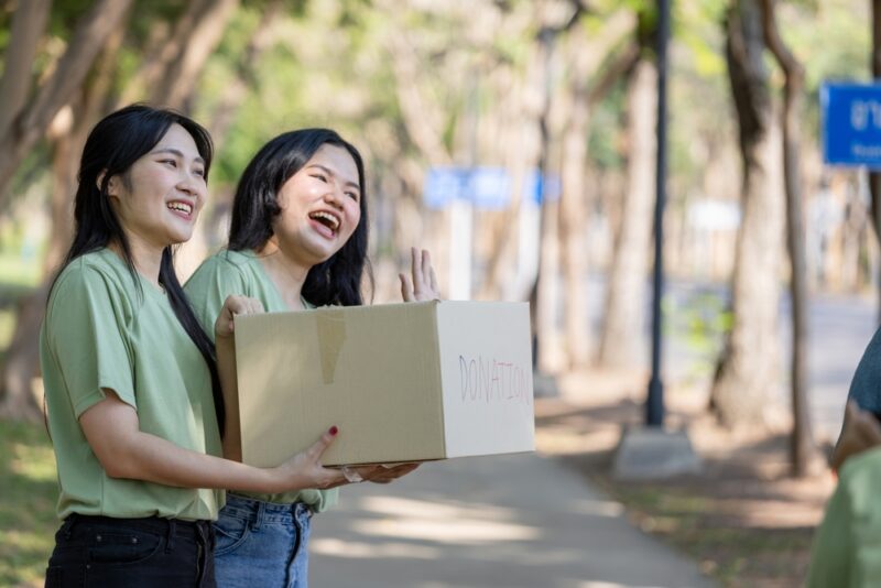 Happy Volunteers Helping the Community with Donations, Smiling Volunteers Engaged in Donation Activities Outdoors