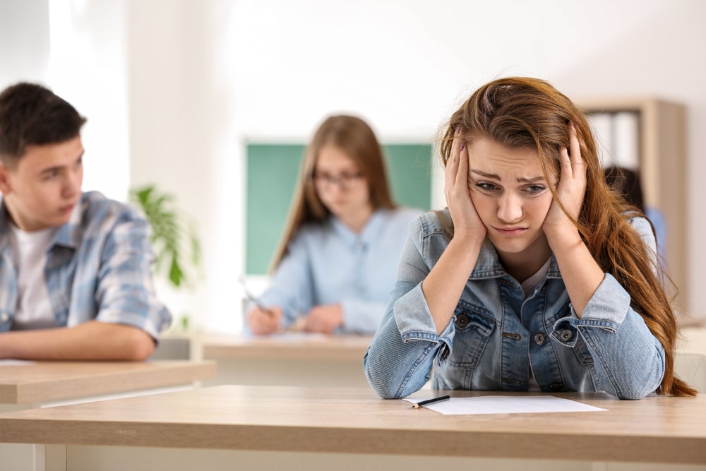 Stressed girl passing school test in classroom