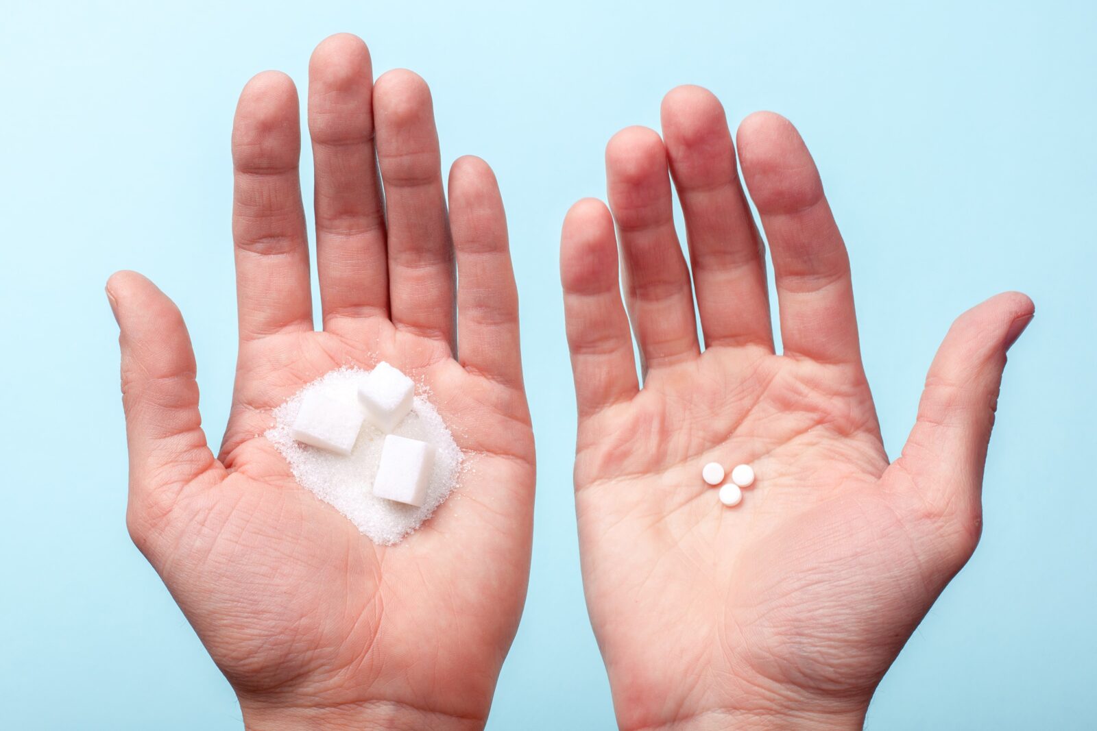 one hand with sugar cubes and the other hand with artificial sweeteners