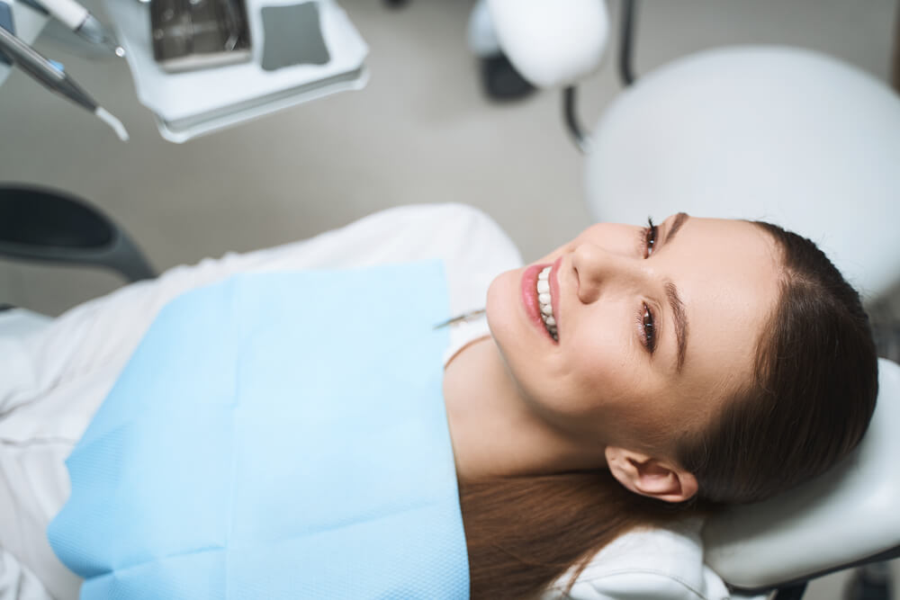 Happy young female is lying in dental chair