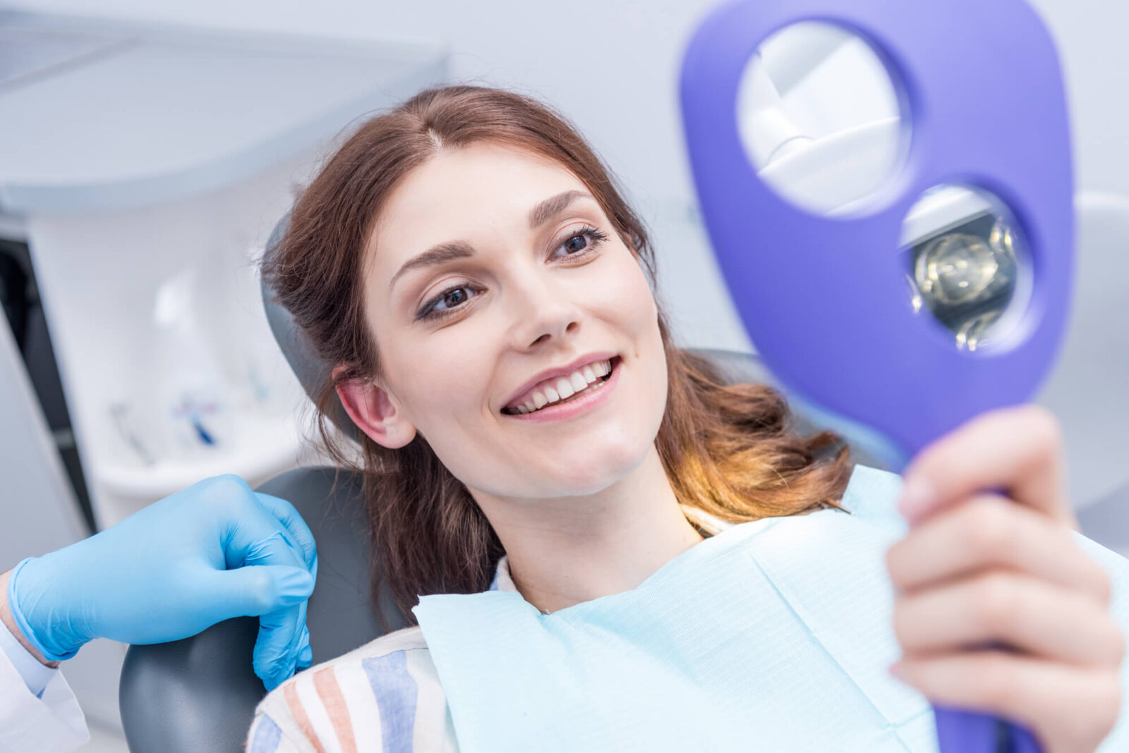 a female patient with dental crowns in coral springs looking in the mirror