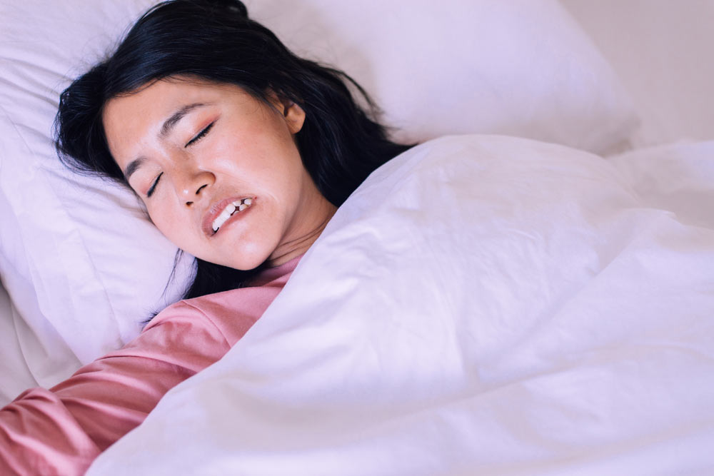Woman sleeping and grinding teeth in bedroom