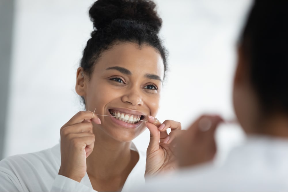 Beautiful smiling young woman holding dental floss