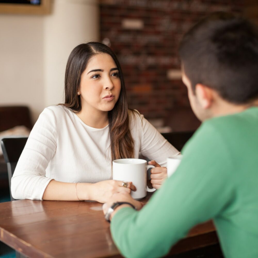 young girl drinking coffee talking with a male