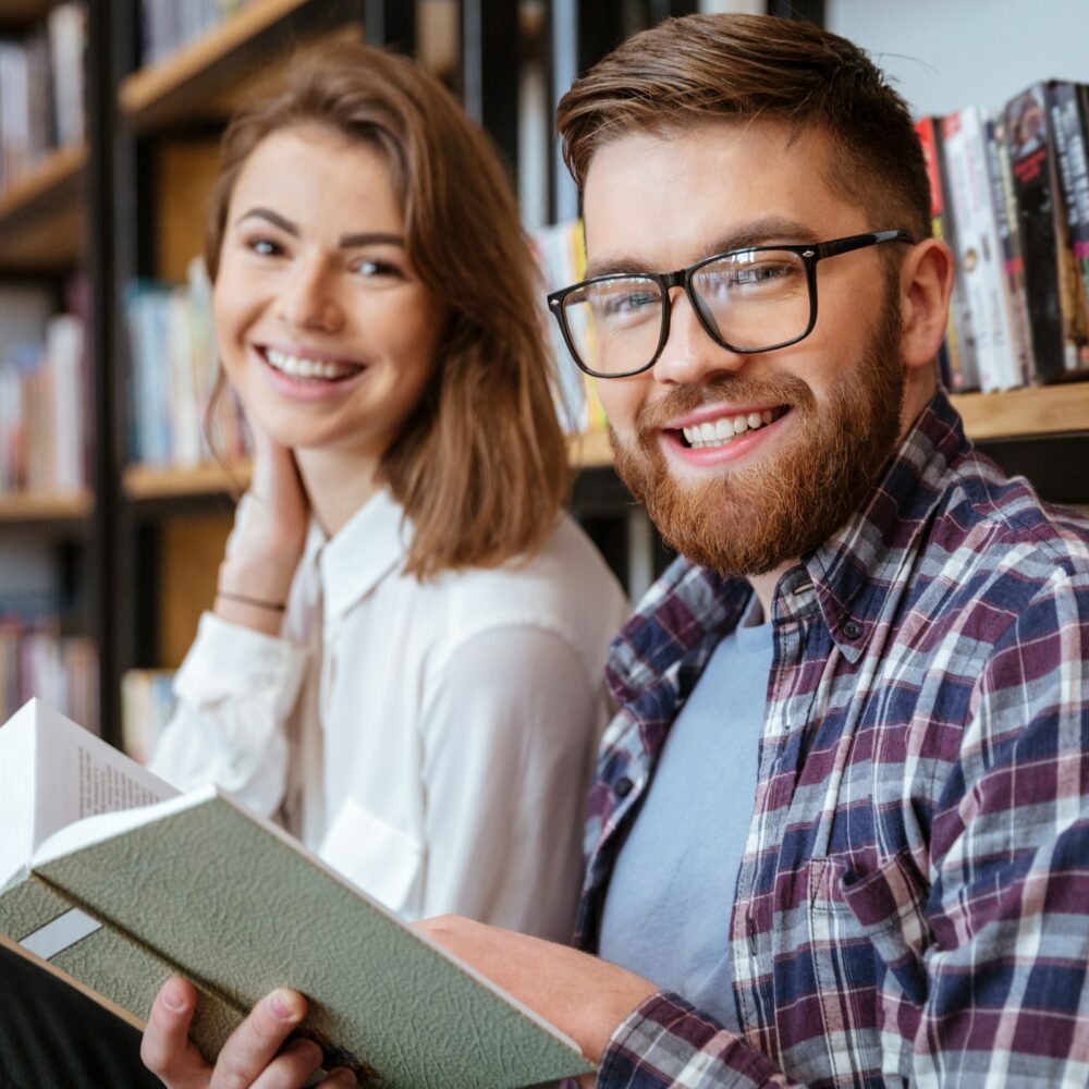 Happy young couple smiling and reading book