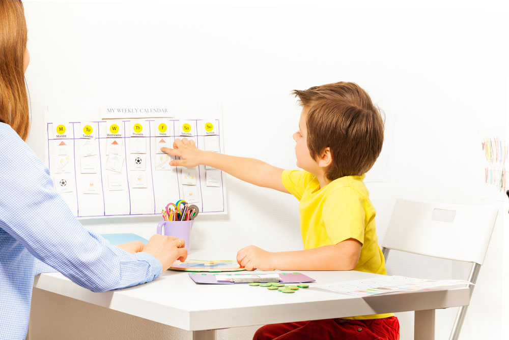 Parent and child collaboratively planning summer schedule using calendar to reduce anxiety