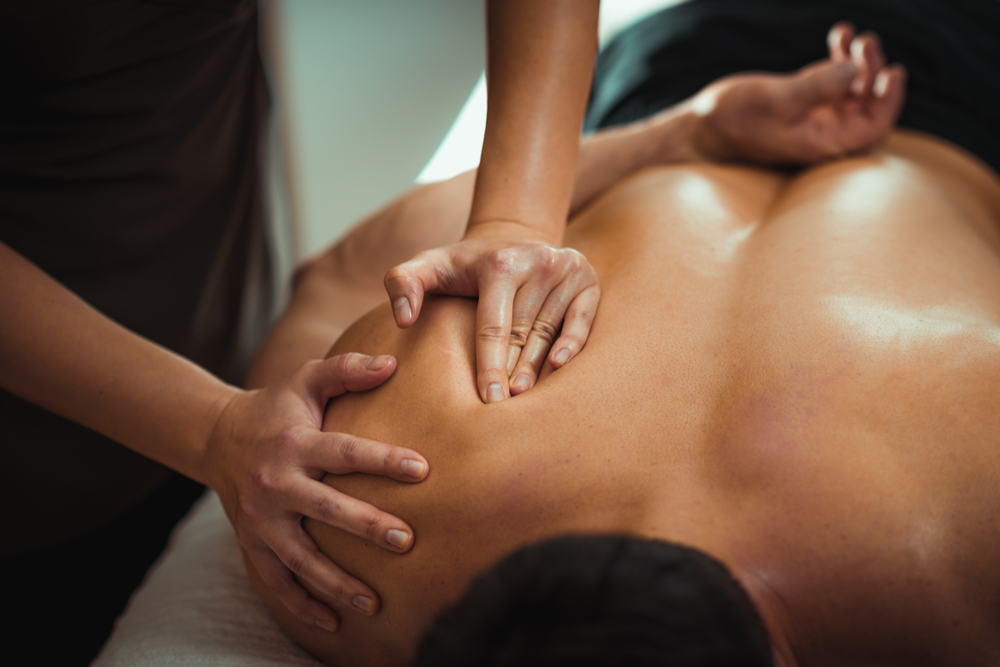 Physiotherapist massaging male patient